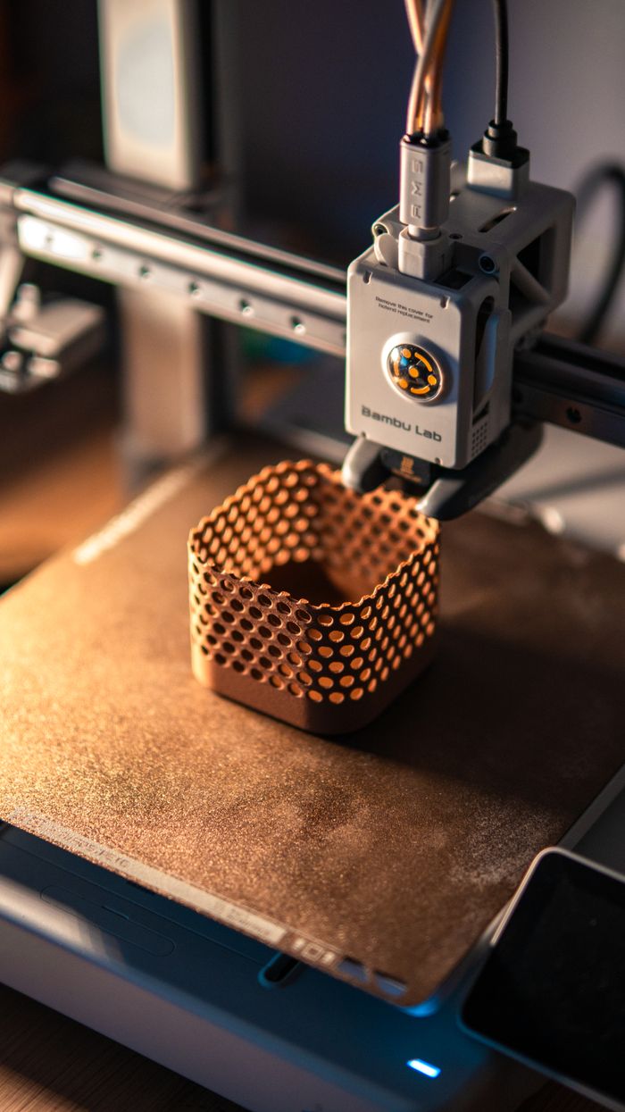 Home Close-up of a 3D printer creating a hexagonal object in a dimly lit workspace.
