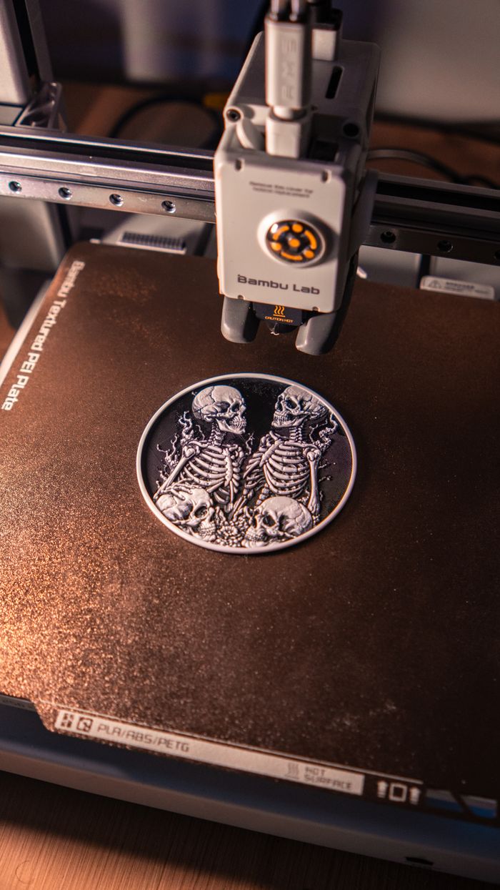 Menus Close-up of an intricate 3D printed skeleton artwork being created on a 3D printer, showcasing digital craftsmanship.