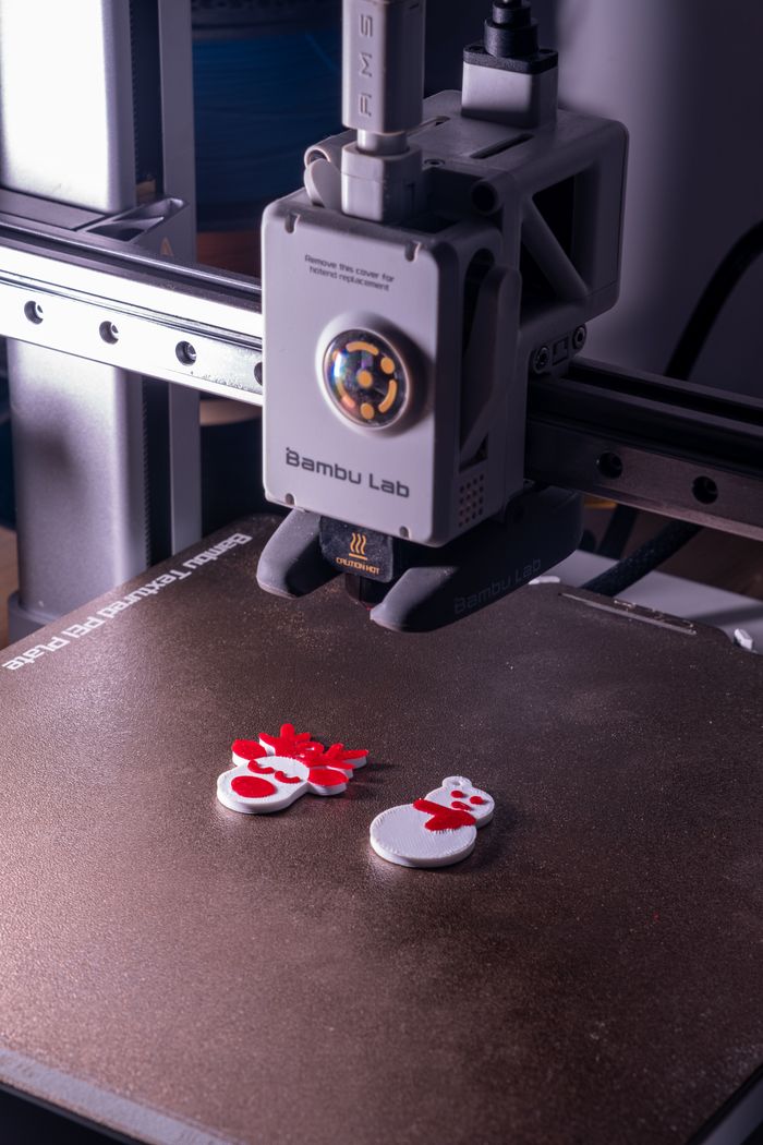 Close-up of a 3D printer creating vibrant snowman decorations, embodying modern technology and festive spirit.