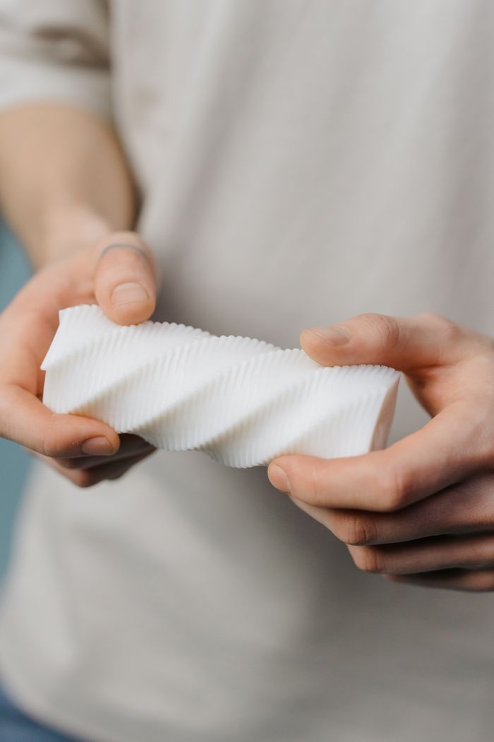 About Detailed view of hands grasping a modern spiral-shaped plastic piece.